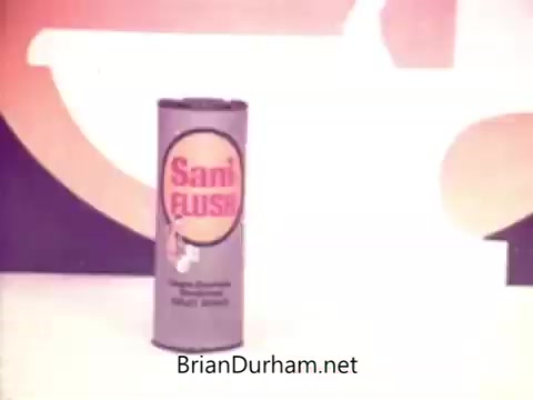 The still features a cylindrical packaging for Sani-Flush, positioned prominently against a colorful backdrop typical of 1970s advertising. The canister is gray with a bold logo that includes the brand name in a vibrant color, emphasizing its cleaning capabilities. The design reflects the aesthetics of that era, aimed at attracting consumer attention. Sani-Flush was marketed as a powerful toilet bowl cleaner, showcasing the effectiveness of its main ingredient, sodium bisulfate.