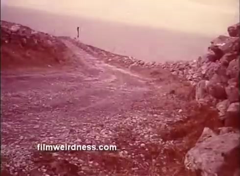 The still from the trailer of 'The Mackintosh Man' depicts a rugged, rocky path leading towards a distant horizon, suggesting a sense of isolation and intrigue. The muted colors and natural textures evoke a gritty atmosphere, fitting for a suspenseful narrative featuring espionage and deception, often associated with Paul Newman’s roles. This setting hints at the film's themes of conflict and pursuit.