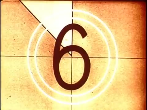 The still from '16mm leader China Girls' features a countdown with the number '6' prominently displayed in the center. The background consists of a textured amber color with circular overlays, typical of film leader visuals. This type of footage was used for calibration, allowing film lab technicians to adjust color and exposure levels accurately before processing the main film.