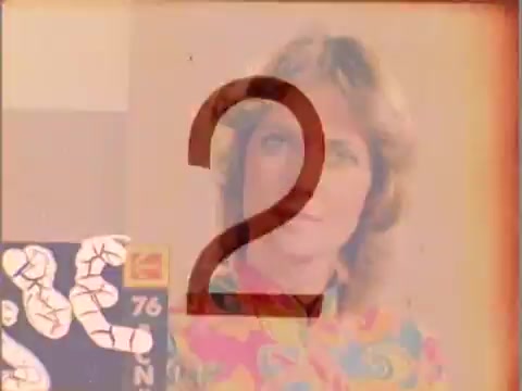 The still features a colorful background with a woman appearing prominently in the center, likely used as a color reference for film processing. The number '2' overlays the image, indicating a sequence in the film leader. The image showcases the vibrant colors typical of 16mm film leader tests, highlighting the cultural aspect of the period.