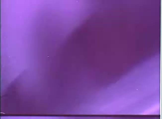 The still from 'The Adventure of Sherlock Holmes' Smarter Brother' trailer features a predominantly purple background with subtle shades and variations. There are faint highlights, possibly stars or light reflections, suggesting a whimsical or mysterious atmosphere. The image reflects a cinematic feel, likely capturing the quirky tone of the film.