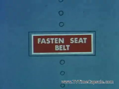 The still features a prominent sign that reads 'FASTEN SEAT BELT,' likely emphasizing safety in various environments, paralleling the message about being alert to safety signals like pesticide labels. It suggests the importance of following safety guidelines in daily life to ensure personal well-being.