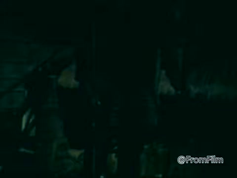 The still from the 1975 PSA 'Columbian Fathers' depicts a dimly lit scene, likely conveying a somber or serious tone. The figures present are partially obscured, emphasizing a sense of anonymity or focus on action rather than individuals. This aligns with the typical aims of public service announcements, often focused on conveying a message about community or faith.