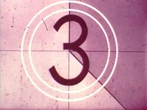 The still depicts a countdown frame commonly used in film, showing the number '3' enclosed in concentric circles. This visual signals the impending start of a film segment, likely from the 1973 Chun King Chinese Food commercial featuring Mama Cass's mother and Charles Louie. The vintage style, characteristic of 16mm film, adds a nostalgic touch. This frame is a unique Christmas gift, showcasing your family's thoughtfulness by sourcing a piece of cinematic history.