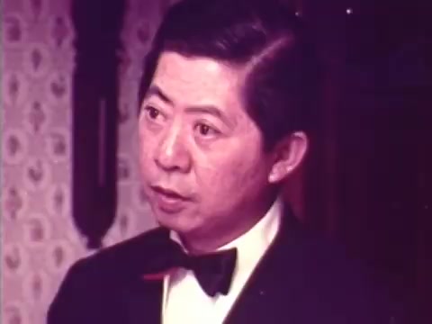 The still features a well-dressed man in a tuxedo, likely Charles Louie, showcasing an expression of engagement or concern. The background suggests a cozy indoor setting, complementing the theme of the commercial. This 16mm still captures a nostalgic moment from the 1973 Chun King Chinese Food advertisement, highlighting the charm of its time and the connection to your family's thoughtful Christmas gift.