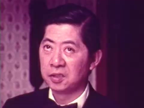 The still captures a moment from the 1973 Chun King Chinese Food commercial featuring Charles Louie. He appears in formal attire, looking serious and engaged, set against a backdrop with subtle patterns typical of the era. This commercial reflects a nostalgic glimpse into food advertising of the time. It's a special Christmas gift, showcasing your family's effort to connect with a piece of vintage media history from a trusted vendor.