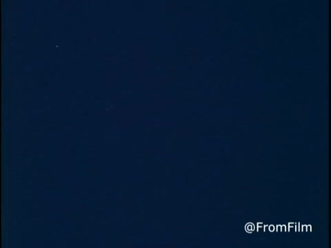 The still from 'C&P Telephone - Operator talks Long Distance Rates - 1970's' features a telephone operator explaining the nuances of long-distance calling rates. Emphasizing that rates increase on Sundays at 5 PM, she encourages viewers to make calls earlier in the weekend, specifically on Saturday and until 5 PM on Sunday, to save money. The visual likely reflects the era's aesthetic and illustrates the communication methods of that time.