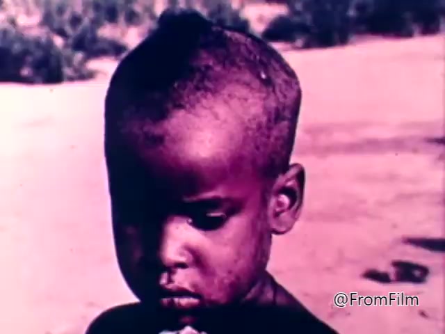 The still from the 1975 CARE World Hunger Fund PSA features a young child with a closely cropped hairstyle, looking down with a somber expression. The background appears desolate, suggesting a harsh environment. The image conveys a poignant message about hunger and the plight of children in impacted regions. The overall tone is serious, aimed at raising awareness for the hunger crisis.