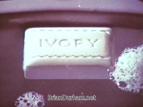 The still features a bar of Ivory Soap prominently displayed in a shallow dish with bubbles around it. The soap has 'IVORY' embossed on its surface, emphasizing the brand. The overall tone is nostalgic, reflecting the clean and simple aesthetic typical of commercials from the late 1960s.