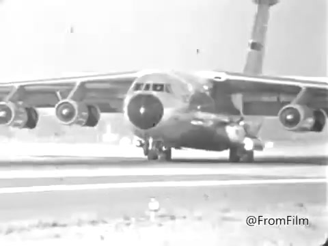 The still features a mid-20th century aircraft, likely a cargo plane, on a runway, showcasing the aviation aspect of military service. It connects to the theme of the Air Force Reserve Recruiting commercial from 1969, emphasizing the role of flight nurses in military operations. The scene evokes a sense of duty and service in a historical context, reflecting the era's recruitment efforts.