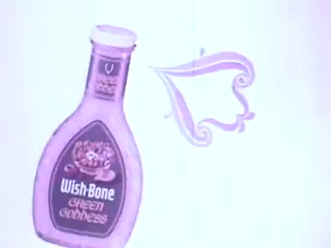 This 16mm still features a bottle of Wish-Bone Green Goddess salad dressing, likely from the late 1960s to 1970. The design showcases a playful and colorful aesthetic, with the dressings' label prominently displayed. An artistic flourish beside the bottle adds a whimsical touch, enhancing the overall charm of the advertisement. Its nostalgic appeal reflects the advertising style of that era, contributing to its high cuteness factor.