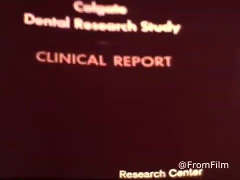 The still from the 1970s Colgate Toothpaste commercial features text that reads “Colgate Dental Research Study” in bold, followed by “CLINICAL REPORT.” The visual design is simple and focused, indicating a formal presentation related to dental health and fluoride's efficacy. The background is likely a solid color, emphasizing the text. This 16mm print captures the era's advertising style, blending scientific credibility with product promotion.