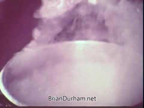 The still from the 1972 Blue Bonnet Margarine commercial shows a pot emitting steam, suggesting cooking or food preparation. The focus on the steam conveys warmth and the appeal of home cooking, which is a common theme in food advertisements. The colors appear warm and vintage, typical of that era in commercial production.