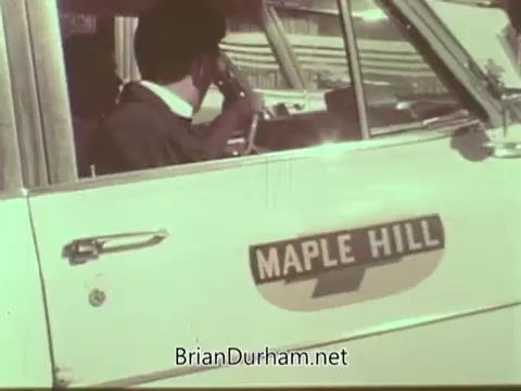 The still depicts a man inside a car, likely a cab, with a visible sign on the door reading 'MAPLE HILL.' He appears to be communicating, possibly on a radio or phone. The image has a vintage aesthetic typical of the 1960s, reflecting the time period of the Aetna Life PSA.