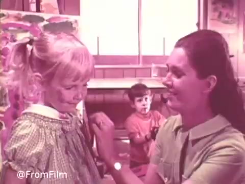 The still features a scene from a vintage commercial for Cold Power Clothes Detergent. A woman is smiling while attending to a young girl with a playful expression, highlighting the family-friendly theme of the brand. In the background, a young boy observes, contributing to a warm, domestic atmosphere. The color palette is soft and nostalgic, typical of mid-20th-century advertising. This scene emphasizes the product's effectiveness in dealing with kids' messes, reinforcing family values.   .
