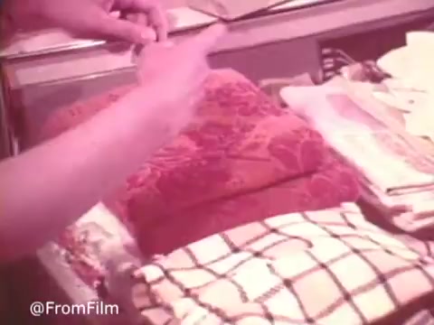 The still from 'Cold Power Clothes Detergent' showcases a person’s hands arranging neatly folded garments on a countertop. The scene emphasizes the detergent's effectiveness, as the vibrant colors of the fabric suggest cleanliness and freshness. The warm tones in the image create a nostalgic feel, reflecting the era of the 16mm print. The overall composition highlights domesticity and the care put into laundry with Cold Power.   .