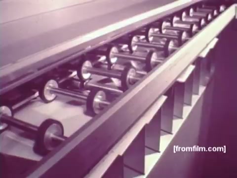 The still from 'IBM: Once Upon A Punched Card' (1964) features a close-up of a mechanical system for handling punched cards. It showcases a series of rollers that likely transport or process the cards, emphasizing the intricate technology behind early computing methods. The vintage aesthetic of the 16mm print adds a nostalgic touch, highlighting the historical significance of punched cards in computing.   Follow us on Twitter @FromFilm.