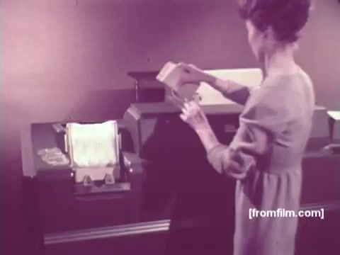 The 16mm still from 'IBM: Once Upon A Punched Card' (1964) depicts a woman interacting with a punched card machine. She is shown about to insert a punched card into the device, highlighting the process of early data input in computing. The scene reflects the historical significance of punched cards as a means of data processing and storage during that era. The background is likely minimalistic, emphasizing the machine's functionality, typical of its time. Overall, it captures a moment that is crucial to the evolution of computing technology.   Follow us on Twitter @FromFilm.