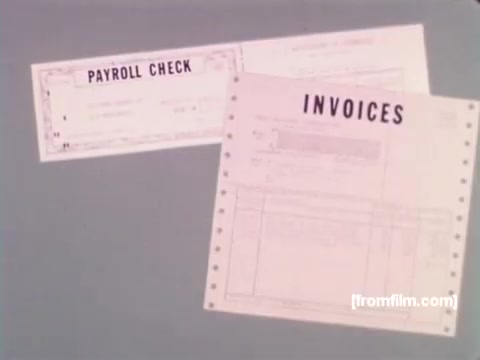 The 16mm still from 'IBM: Once Upon A Punched Card' (1964) features two punched cards prominently displayed: one labeled 'PAYROLL CHECK' and another 'INVOICES.' These cards represent the practical applications of punch card technology in business processes during the era. The visual emphasizes the evolution of data recording and processing, showcasing how these cards played a crucial role in handling financial information.   For more insights, follow us on Twitter @FromFilm.