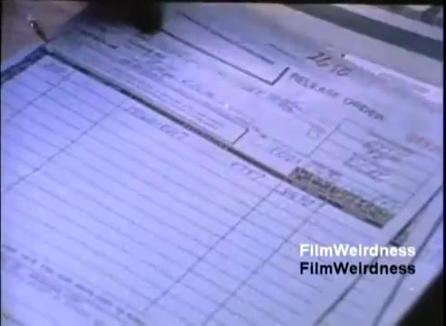 The still shows a close-up of a form labeled 'RECEIVE ORDER.' It appears to be a business document filled out by hand, likely associated with order processing. The text is partially visible, indicating fields for information like item descriptions and quantities. The scene captures a moment of administrative work typical for the era, reflecting the manual processes used before widespread digitization. The overall tone of the image is practical and straightforward.