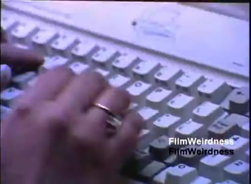 The still shows a close-up of hands typing on an IBM System/36 keyboard. The keyboard features a beige color with distinctive key layouts typical of the era. A hand wearing a ring is visible, suggesting a focus on professional usage. The context is likely related to demonstrating the capabilities or features of the IBM System/36 in a sales presentation from 1984.