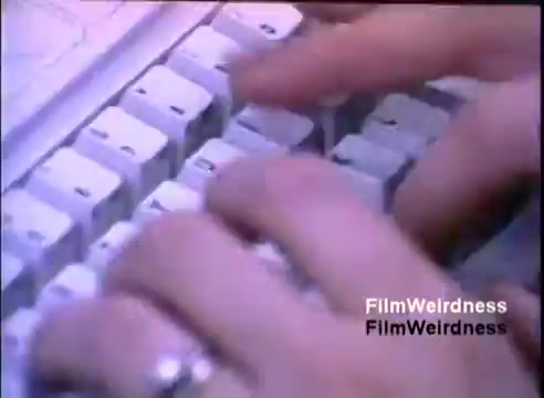 The still features close-up shots of hands typing on a keyboard, showcasing the IBM System 36. The image captures the act of typing, emphasizing the technology's user interaction during the 1984 sales film. The keys appear prominently, indicating a focus on the computing experience of that era.