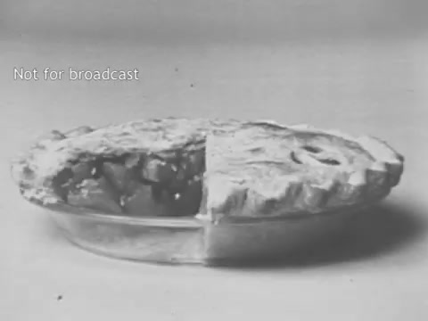The still features a glass pie dish containing a pie that has been cut in half, revealing its filling. The crust appears golden and flaky, while the interior showcases what looks like apple filling. The monochrome presentation gives it a vintage aesthetic, typical of mid-20th century advertising, emphasizing the appeal of the product in a nostalgic and wholesome manner. The text 'Not for broadcast' indicates that this is a draft or unreleased material.