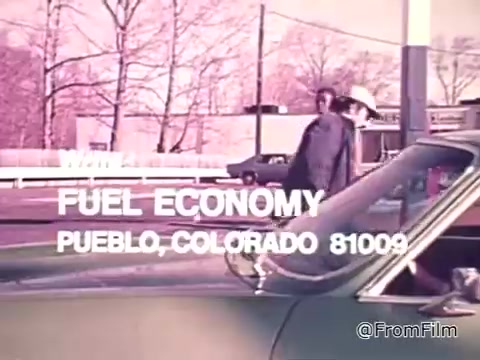 The still depicts a scene from a 16mm film titled 'New Federal Fuel Economy Standards 1975.' It features text that emphasizes the importance of fuel economy. A man walks past a car, and there's a focus on checking gas mileage as a response to rising fuel costs. The location is identified as Pueblo, Colorado, reflecting a time when fuel efficiency became a significant concern for consumers.
