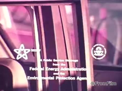 The 16mm still from 'New Federal Fuel Economy Standards 1975' features a close-up view of a car window, showcasing a public service message. The text indicates the involvement of the Federal Energy Administration and the Environmental Protection Agency. The context suggests a focus on rising fuel costs and the importance of checking fuel efficiency stickers when purchasing a vehicle. The image emphasizes the need for consumer awareness regarding gas mileage in the wake of rising gas prices.