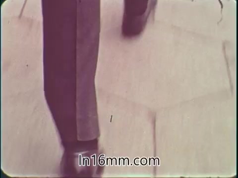 The still from the 'College Fund PSA - 1960's' features a close-up shot of feet walking along a patterned pavement. The image has a vintage aesthetic, typical of 16mm film from that era, with a slightly muted color palette. The focus on the feet suggests a journey or progress, aligning with the educational theme of the public service announcement.