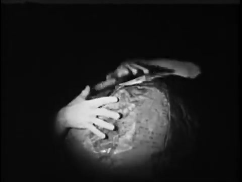 The still from the 1967 'Save The Children' commercial featuring Jack Klugman shows a close-up of hands gripping a textured, spherical object, likely representing the globe. The image is dimly lit, enhancing the emotional weight of the scene, emphasizing themes of global care and concern for children in need.