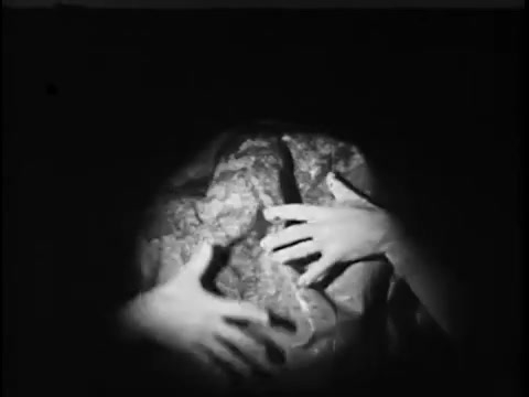 The still from the 1967 'Save The Children' commercial featuring Jack Klugman shows a close-up of hands reaching out to grasp a textured surface. The lighting creates a dramatic, shadowy effect, emphasizing the emotional and urgent nature of the scene. The overall tone suggests themes of vulnerability and a plea for assistance.