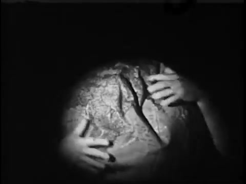 The still from the 1967 'Save The Children' commercial features a close-up of hands gently holding a globe. The focus on the globe suggests a theme of global awareness and responsibility, likely emphasizing the importance of caring for children around the world. The lighting creates a somber mood, reinforcing the seriousness of the message.