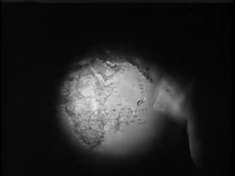 The still features a close-up view of a globe, illuminated from one side. The focus seems to be on a specific region, with visible lines and markings that may represent geographical or political boundaries. The lighting creates a dramatic contrast, highlighting the globe's textures and details while casting shadows around the edges. The overall tone is serious, reflecting the context of a charitable message or awareness campaign associated with Save The Children.