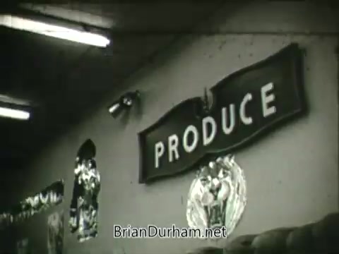 The still from the 'Hire the Handicapped' PSA features a close-up of a sign that reads 'PRODUCE.' The setting appears to be a grocery or market environment, likely emphasizing the importance of employment opportunities in such spaces for veterans and people with disabilities. The context highlights a message of inclusion and the potential for individuals with different abilities to contribute positively to society.