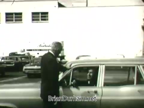 The still from the 'Hire the Handicapped' PSA features a man in a suit speaking to a driver in a car. The setting appears to be a parking lot filled with cars, emphasizing a casual yet earnest interaction. The messaging revolves around supporting veterans and handicapped individuals, highlighting their eagerness to work and contribute positively to society. The tone is motivational, urging viewers to recognize the abilities of these individuals.