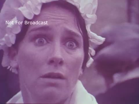 The still from the 'Molly Pitcher Bicentennial Savings Bonds PSA' captures a woman in period costume, likely portraying Molly Pitcher. She has a distressed expression with wide eyes, suggesting a moment of surprise or concern. The scene emphasizes historical themes, aligning with the bicentennial narrative. The soft, muted colors reflect the aesthetic of vintage film.