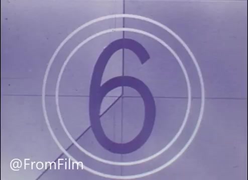 The still from 'Morgan Freeman singing TV Commercial - John Hancock Insurance' features a countdown frame, specifically showing the number '6' within concentric circles. This indicates it's part of a film reel, typically used to signify the start of a scene or segment. The style is characteristic of older film formats, emphasizing a nostalgic aesthetic. The title noted is 'The Happy Freemans.'