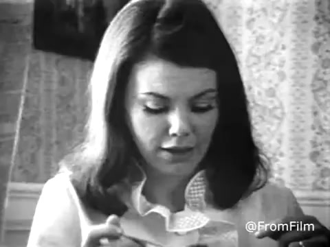 The still from the Sanka Coffee commercial features a woman, presumably Marsha Mason, focused on a cup in her hands. The image has been converted to black and white, showcasing muted details against a textured background, likely an old floral wallpaper typical of the era. The ambiance suggests a domestic setting, emphasizing comfort and warmth associated with coffee drinking. The commercial likely aims to convey a relaxed, inviting atmosphere around Sanka Coffee. The mention of Sanka meaning 'terrible disaster' adds a playful curiosity to the narrative.