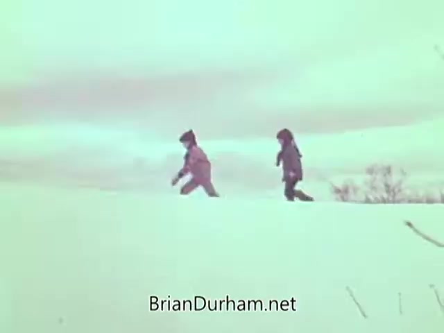 The still from the 1968 'Christmas Seal PSA' depicts two children walking through a snowy landscape. They are dressed warmly, reflecting a winter scene. The overall tone evokes a sense of innocence and joy associated with the holiday season, aligning with the message of the PSA aimed at promoting awareness and support for the Christmas Seal campaign.