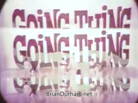 The still from the '1968 Ford Mustang Commercial' features a vibrant, dynamic display with the bold phrase 'GOING THING' repeated in large letters, creating a visually striking effect. Arte Johnson, known for his comedic work on 'Laugh-In,' appears in character, likely contributing humor to promote Ford's Pop-Option sale. The scene suggests an upbeat atmosphere typical of late '60s advertising, aimed at engaging viewers on WTRF in Wheeling, West Virginia. The overall vibe captures the excitement and flair of the era, aligning with Ford's marketing strategies to attract customers.