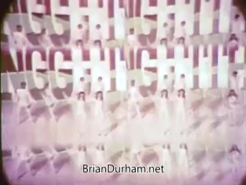 The still from the 1968 Ford Mustang commercial features a vibrant, playful backdrop with the word 'GOING' repeated in a dynamic, eye-catching manner. Arte Johnson, known for his comedic style on 'Laugh-In,' brings a lighthearted tone to the promotion. The aesthetic is typical of the late 60s, incorporating bold colors and energetic visuals to grab the audience's attention, fitting for a local broadcast on WTRF in Wheeling, West Virginia. The commercial is aimed at promoting Ford's Pop-Option sale, with a focus on excitement and fun.