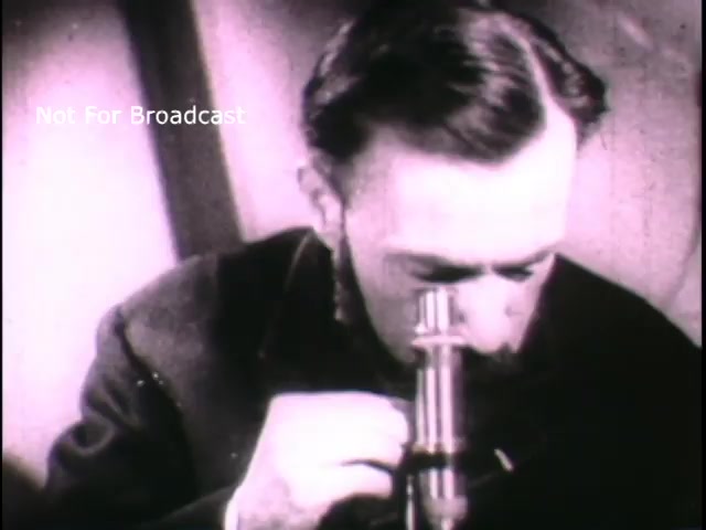 The still depicts a historical figure, presumably Louis Pasteur, intently looking through a microscope. The image captures the essence of scientific inquiry and discovery, highlighting the importance of research in medical advancements. The monochrome quality suggests it is an older film, likely emphasizing the contributions of Pasteur to microbiology and public health. The watermark indicates the image is not for broadcast use.
