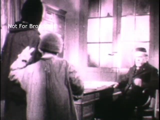 The still features a historical scene set in a dimly lit room with two figures, one standing and one appearing to be seated at a desk. The seated figure is likely portraying a character based on Louis Pasteur, conveying an air of authority or contemplation. The overall tone is serious, reflecting a moment of significance likely related to Pasteur's contributions to science and public health, as suggested by the context of a US Army PSA. The image is presented in black and white, which emphasizes its historical nature.