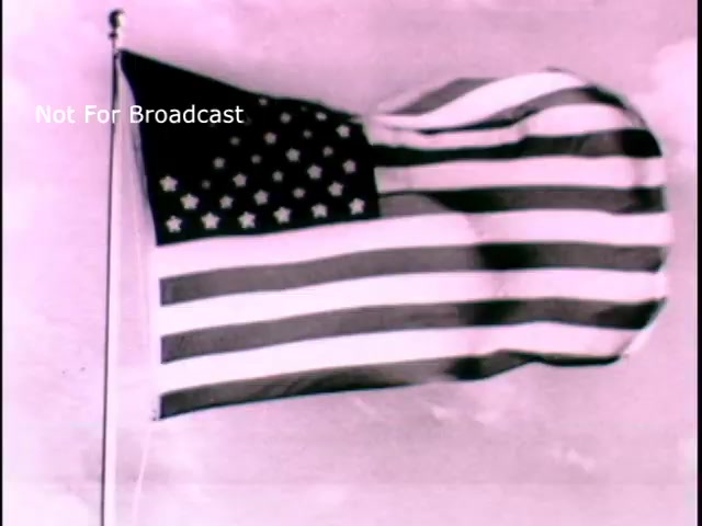 The still features a waving American flag, set against a light background, likely evoking themes of patriotism and national pride. The visual style may reflect the historical context of the PSA, emphasizing America's values and contributions, particularly in relation to Louis Pasteur's legacy in science and medicine. The watermark indicates that the image is not intended for broadcast.