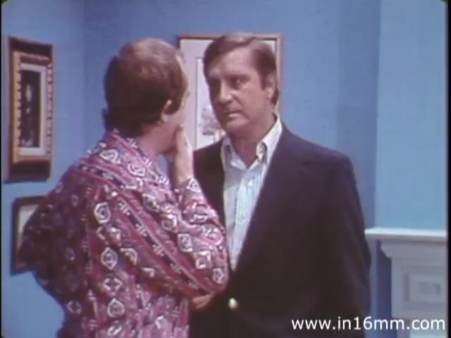 'I Am Joe's Stomach,' a 1980s production from Reader's Digest, utilizes a combination of three-dimensional animation and live-action sequences to explore the functions of the human stomach. The storyline follows a figurative character, Joe, who encounters various issues related to digestion and bowel health. In the still, two male characters are engaged in a conversation, suggesting a moment of critical discussion or concern that highlights the film's educational tone, emphasizing the importance of stomach care while adding a touch of humor to the serious subject of digestive health. The setting features a simple interior with blue walls and framed artwork.