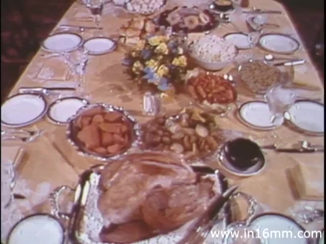 The still from 'I Am Joe's Stomach' (1980s version) showcases a lavishly set dining table laden with an array of food. The focus appears to be on a large roasted turkey as the centerpiece, surrounded by various side dishes, including vegetables and desserts. The table is elegantly arranged, complete with fine dishware and glassware, suggesting a festive or special occasion. This visual emphasizes the theme of consumption and its impact on digestion, aligning with the film's exploration of stomach functions through the narrative of Joe's experiences.