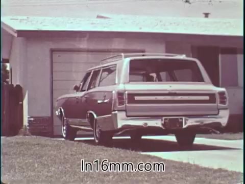 The still from the PSA features a vintage car, a station wagon, parked in front of a suburban home. The focus on the vehicle reflects the context of the voice-over, emphasizing safety in automobile driving. The setting conveys a typical 1960s American neighborhood, aligning with Shirley Shahan's identity as a professional driver advocating for safety in drag racing.