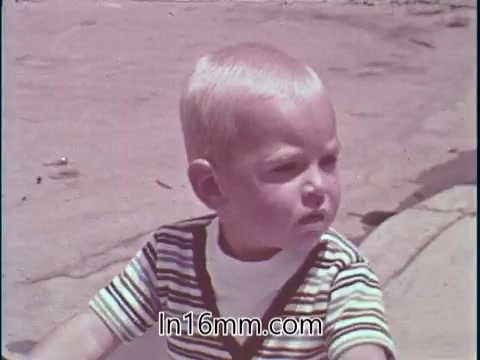 The still from the PSA features a young boy with a serious expression, dressed in a striped shirt. He appears to be outside, perhaps observing his surroundings. The focus on the child contrasts with the theme of the voice-over emphasizing safety in the context of drag racing, particularly as it relates to Shirley Shahan's perspective on the sport. The boy's demeanor could symbolize the innocence and future implications of road safety education.