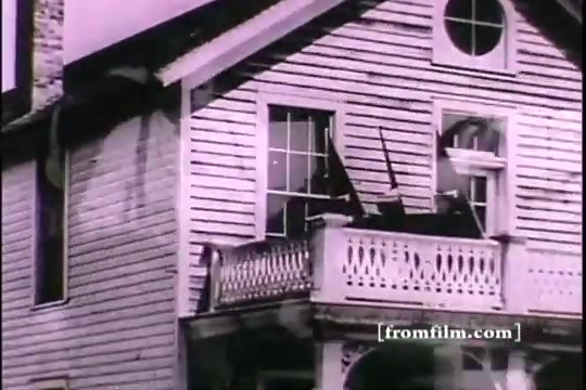 The still features the exterior of a wooden house with a balcony. A few firearms are propped against the balcony railing, suggesting a historical military or recruitment theme. The image appears to be from a vintage 16mm print, likely presenting a dramatization related to Thomas Edison and the context of army recruiting. The overall style reflects early 20th-century filmmaking aesthetics.